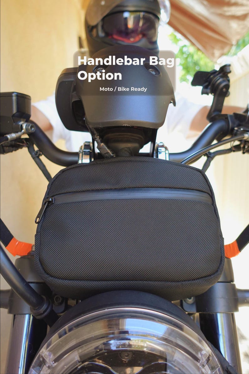 May include: Black handlebar bag with a zipper closure, mounted on a motorcycle. The bag is rectangular and has a textured surface. The text "Handlebar Bag Option" and "Moto / Bike Ready" are visible.