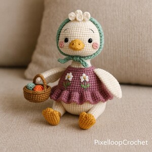 May include: A handmade crochet duck doll with a cream-colored body, wearing a purple dress with white flower embroidery. The duck has a yellow beak, orange feet, and a green bonnet. It holds a small basket with colorful eggs.