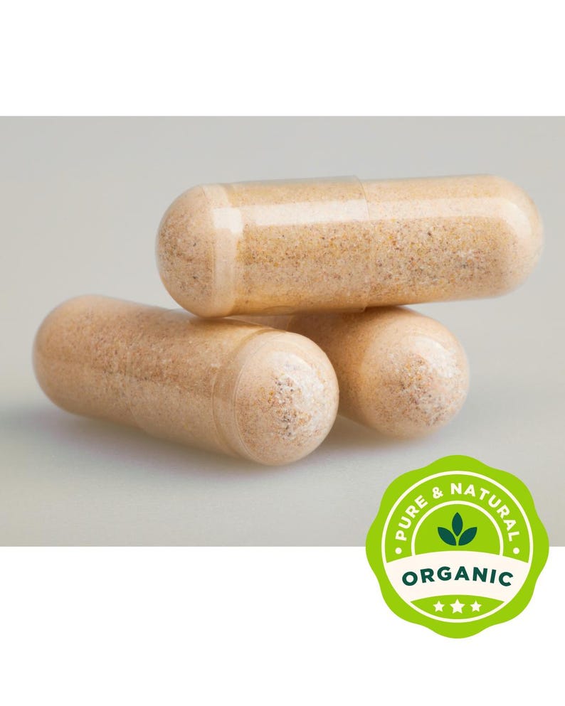 May include: Close-up of three beige capsules, stacked. The capsules are filled with a light brown powder. A green and white circular label with the words "Pure & Natural" and "Organic" is in the lower right corner.
