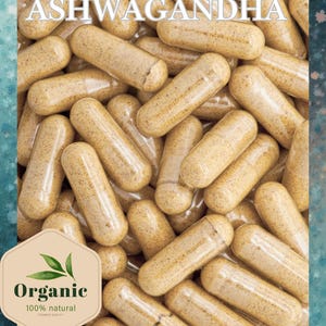 May include: Close-up of Ashwagandha capsules, a natural supplement. The capsules are light brown and filled with a powder. The image includes the text "Withania Somnifera Ashwagandha" and an "Organic" label, indicating a focus on natural health products.