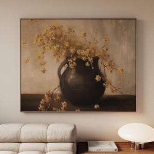 May include: A framed painting of a dark brown vase overflowing with yellow flowers. The vase is on a dark surface, set against a neutral backdrop. The artwork is displayed in a living room setting.