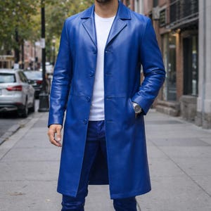 Peut inclure: Un long manteau en cuir bleu vif avec une fermeture boutonnée classique. Le manteau présente un col à revers, des poches avant et une coupe ajustée. La personne porte un t-shirt blanc et un jean bleu.
