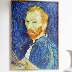Peut inclure: Impression d'art encadrée d'un portrait d'homme aux cheveux roux et à la barbe rousse, vêtu d'une veste bleue. L'œuvre d'art présente un fond bleu et est exposée sur un mur blanc. Un vase blanc et une table en bois sont au premier plan.