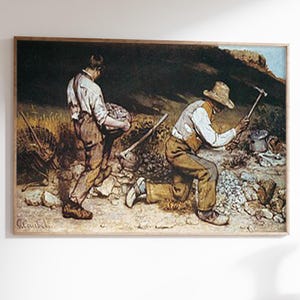 May include: A framed print of a classic painting depicting two men working on a rocky terrain. One man carries a basket, while the other kneels, hammering stones. The artwork features muted tones and a rustic aesthetic, suitable for home decor.