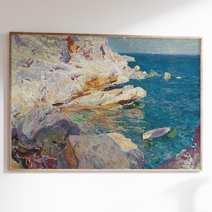 Op de afbeelding: Olieverfschilderij van een kustlandschap met witte kliffen, turquoise water en een kleine boot. Het kunstwerk is ingelijst in een goudkleurige lijst. Het schilderij wordt tentoongesteld op een houten bureau met een witte vaas en een houten stoel met gouden accenten.