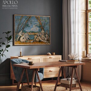 May include: A framed print of a classical painting hangs above a wooden cabinet and desk. The artwork depicts figures in a landscape with blue and green hues. The desk has a blue chair, a coffee cup, and a woven basket. The text "APOLLO TIMELESS PRINTS" is visible.