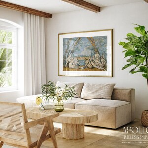 May include: A living room scene featuring a large framed print with a gold frame, depicting figures in a classical style. The room includes a beige sectional sofa, a wooden coffee table, and a woven chair. A potted plant adds a touch of greenery.