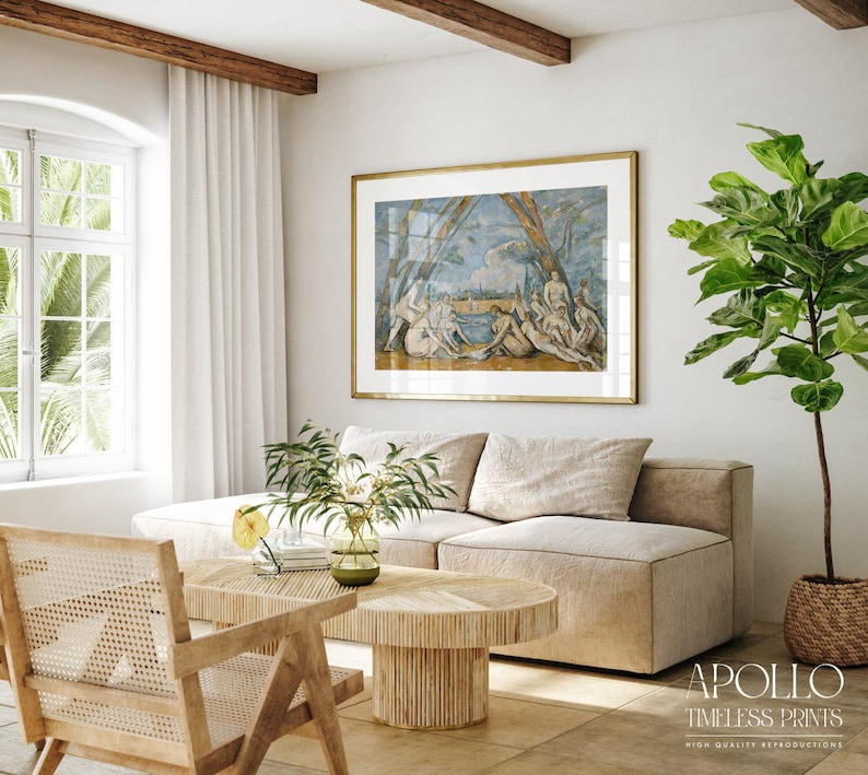 May include: A living room scene featuring a large framed print with a gold frame, depicting figures in a classical style. The room includes a beige sectional sofa, a wooden coffee table, and a woven chair. A potted plant adds a touch of greenery.