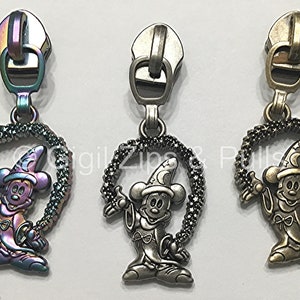 May include: Three zipper pulls featuring a cartoon image of Mickey Mouse dressed as a magician. The zipper pulls are available in three finishes: iridescent, silver, and gold.