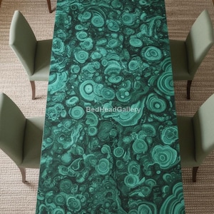 Op de afbeelding: Een rechthoekige tafel met een levendig groen malachietpatroon. De tafel is omringd door vier groene gestoffeerde stoelen. Het malachietontwerp heeft wervelende patronen en cirkelvormige vormen.