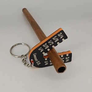 May include: A copper pipe with a wooden handle and a black and orange Lineset O.D. gauge attached to a keychain. The gauge has measurements for pipe sizes.