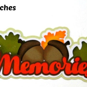 May include: A decorative paper craft with the word "Memories" in red letters, surrounded by green leaves, brown acorns, and orange fall leaves. The craft measures 7 x 2 1/4 inches.