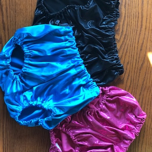 May include: Three pairs of shiny, stretchy, short underwear in black, blue and pink.