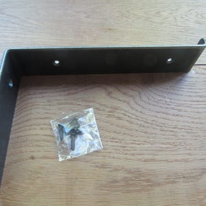 Puede incluir: Un soporte de estante de metal en forma de L con un acabado gris oscuro y un pequeño borde levantado en el extremo. El soporte cuenta con cuatro orificios de montaje circulares preperforados. Se incluye una pequeña bolsa de plástico transparente con tres tornillos.