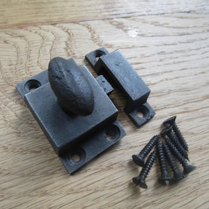 Peut inclure: Un loquet de porte en fonte gris foncé composé d'une plaque de base rectangulaire avec un bouton ovale central et une gâche séparée. Le kit de quincaillerie comprend six vis noires assorties à tête plate pour la fixation sur une porte.