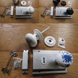 May include: A rim lock set featuring a rectangular silver metal plate with a keyhole, a white porcelain knob with a blue floral pattern, a matching white porcelain rosette, two skeleton keys, a metal strike plate, and a bag of mounting screws.