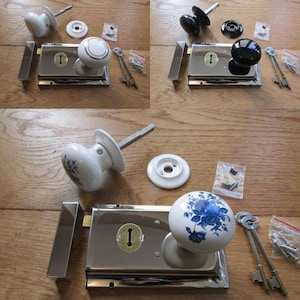 Könnte beinhalten: Ein Aufschloss-Set bestehend aus einem rechteckigen Schlosskasten aus poliertem Chrom, einem runden Keramikknauf mit blauem Blumenmuster, einer passenden runden Rosette, zwei Skelettschlüsseln sowie einem Beutel mit Schrauben und Zubehör.