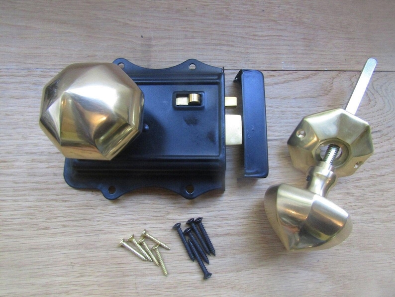 K&ouml;nnte beinhalten: Ein Kastenschloss-Set bestehend aus einem schwarzen, rechteckigen Metallgeh&auml;use mit einem polierten, achteckigen Messingknauf. Ein separater, passender achteckiger Messingknauf mit Vierkantstift, ein Schlie&szlig;blech und kleine Schrauben liegen bei.