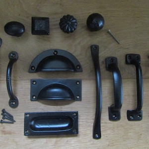 Può includere: Una collezione di ferramenta nera per mobili che include vari pomelli, maniglie a conchiglia e maniglie per cassetti. Il set presenta design curvi, dritti e intrecciati, insieme a quattro piccole viti metalliche e un chiodo per il montaggio.