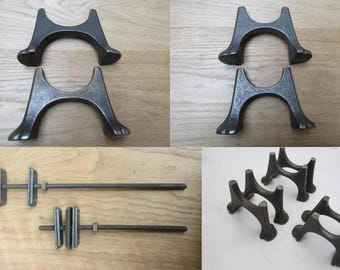 Könnte beinhalten: Ein Set aus vier dunkelgrauen Metallhalterungen mit gewölbten Sockeln und zwei langen Gewindestangen mit verstellbaren Halterungen. Die Komponenten haben eine texturierte Oberfläche und sind für strukturelle Stützen oder Montagezwecke ausgelegt.
