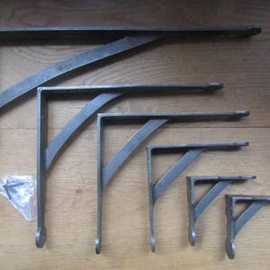 Puede incluir: Un juego de seis soportes para estantes en forma de L de metal en tamaños graduados, con un acabado gris oscuro y un refuerzo diagonal. Cada soporte tiene un detalle circular en el extremo y orificios de montaje. Incluye una bolsa con tornillos.