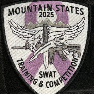 Pode incluir: Patch bordado com o texto "MOUNTAIN STATES 2025 TRAINING & COMPETITION SWAT". O patch apresenta uma águia, asas, um rifle e uma faca, com detalhes em roxo e branco sobre um fundo preto.