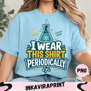 Pode incluir: Uma t-shirt azul-clara com um gráfico de um frasco de laboratório e um símbolo de átomo. O texto diz "lab vibes", "science mode" e "I WEAR THIS SHIRT PERIODICALLY" em letras brancas, amarelas e verde-azulado com um ícone molecular.