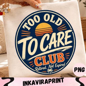 May include: A white fabric surface featuring a circular graphic with a dark blue background. The design includes a yellow sunset, a palm tree icon, and the text "TOO OLD TO CARE CLUB" in bold, distressed lettering, with "Retired. Not Expired." below.