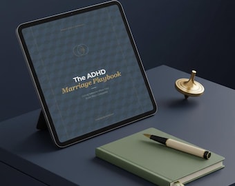May include: A digital tablet displaying "The ADHD Marriage Playbook" with a gold and navy blue geometric design. A green notebook, pen, and gold spinning top are on a dark blue surface.