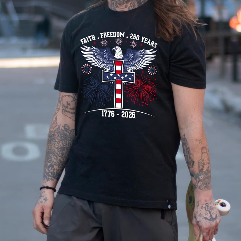 May include: Black t-shirt with a patriotic design featuring an eagle, cross, and fireworks in red, white, and blue. Text includes "Faith. Freedom. 250 Years" and "1776-2026".