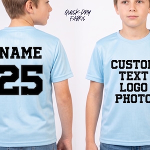 May include: A light blue short-sleeve t-shirt made of quick-dry fabric. The back features the word NAME and the number 25 in black block lettering. The front displays the black text CUSTOM TEXT LOGO PHOTO in a bold, centered block font style.