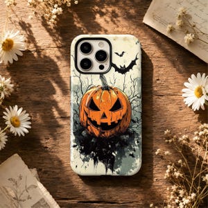 May include: A smartphone case featuring a central orange jack-o'-lantern with a carved face, surrounded by black silhouettes of bats and bare tree branches against a pale, textured background. The design includes a triple-lens camera cutout.