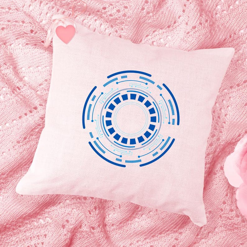 Pu&ograve; includere: Un cuscino quadrato rosa chiaro con un design tecnologico circolare blu e azzurro. Il design presenta cerchi concentrici con un motivo quadrato centrale e linee di collegamento. Un piccolo cuore rosa &egrave; attaccato.