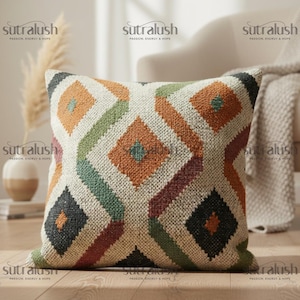 May include: Square throw pillow with a geometric diamond pattern in orange, green, burgundy, and black on a cream background. The pillow is made of a textured fabric and has the text "sutralush PASSION, ENERGY & HOPE" repeated on the image.