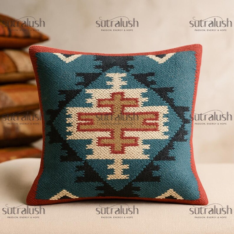 May include: Square decorative pillow with a geometric pattern in teal, black, cream, and red. The pillow has a red border and features a central cross-like design. The text "sutralush" is visible in the corners.