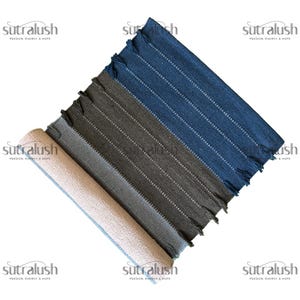 Peut inclure: Quatre tapis rectangulaires tiss&eacute;s, enroul&eacute;s et d&eacute;roul&eacute;s, dans des tons beige, gris et bleu. Chaque tapis pr&eacute;sente des rayures verticales blanches et des bords frang&eacute;s. Les tapis sont dispos&eacute;s en diagonale, mettant en valeur leurs couleurs et textures vari&eacute;es.
