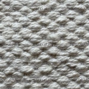 Peut inclure: Gros plan sur un tissu textur&eacute; gris clair avec un motif en relief r&eacute;p&eacute;titif. Le motif ressemble &agrave; de petites bosses ou touffes arrondies, cr&eacute;ant un effet tridimensionnel. Le tissu a un aspect doux et invitant.