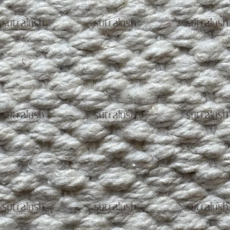 Peut inclure: Gros plan sur un tissu textur&eacute; gris clair avec un motif en relief r&eacute;p&eacute;titif. Le motif ressemble &agrave; de petites bosses ou touffes arrondies, cr&eacute;ant un effet tridimensionnel. Le tissu a un aspect doux et invitant.