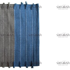 Peut inclure: Gros plan sur deux tapis tiss&eacute;s, un gris et un bleu, avec des rayures verticales blanches et des franges. Les tapis sont faits d'un mat&eacute;riau textur&eacute; et sont probablement destin&eacute;s &agrave; la d&eacute;coration int&eacute;rieure. La marque "sutralush" est visible.