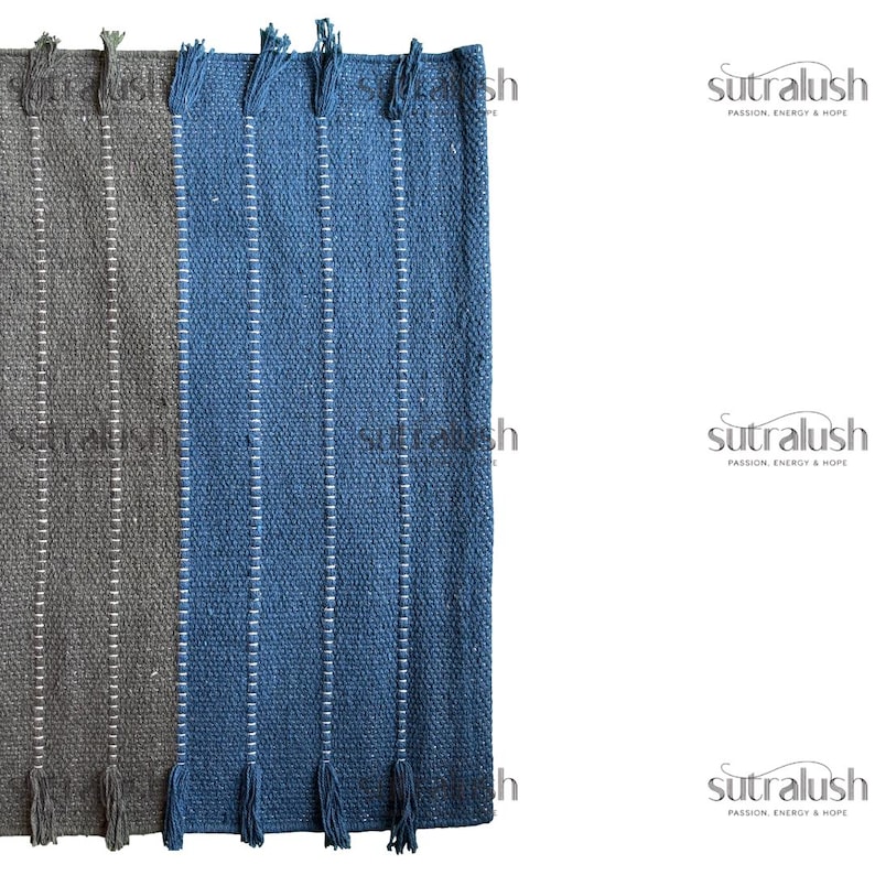 Peut inclure: Gros plan sur deux tapis tiss&eacute;s, un gris et un bleu, avec des rayures verticales blanches et des franges. Les tapis sont faits d'un mat&eacute;riau textur&eacute; et sont probablement destin&eacute;s &agrave; la d&eacute;coration int&eacute;rieure. La marque "sutralush" est visible.