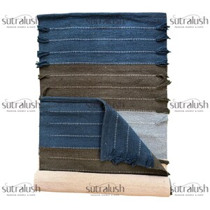 Peut inclure: Un tapis rectangulaire &agrave; rayures horizontales bleues, marron et grises. Le tapis a une section enroul&eacute;e en bas et un bord &agrave; franges. Le tapis est fait de mati&egrave;re tiss&eacute;e.
