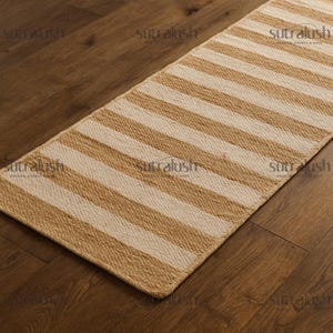 May include: A rectangular, striped rug with alternating beige and off-white bands. The rug is made of a woven material and is placed on a wooden floor. The rug's design is simple and neutral, suitable for various interior styles.