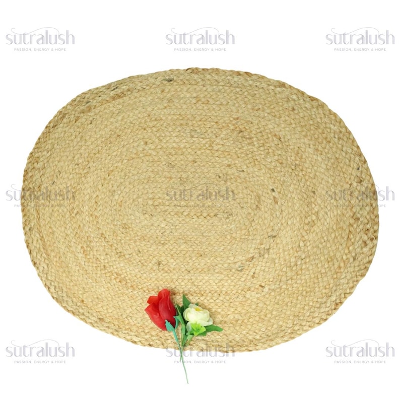 May include: A round, natural jute rug with a woven texture. The rug is a light tan color and has a diameter of approximately 48 inches. A small bouquet of red and white flowers rests on the rug.