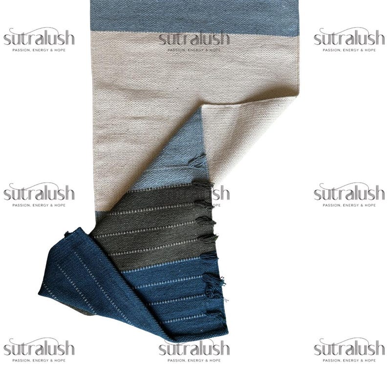 Peut inclure: Un tapis rectangulaire multicolore avec un motif &agrave; rayures bleues, beiges et grises. Le tapis a un aspect textur&eacute; et un bord &agrave; franges. Le nom de la marque "sutralush" est imprim&eacute; sur le tapis.