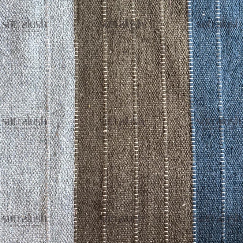 Peut inclure: Gros plan sur un tissu textur&eacute; &agrave; rayures verticales. Le tissu est divis&eacute; en trois sections : bleu clair, marron et bleu fonc&eacute;. Chaque section comporte des coutures blanches verticales. Le mot "sutralush" est visible dans le coin sup&eacute;rieur gauche.