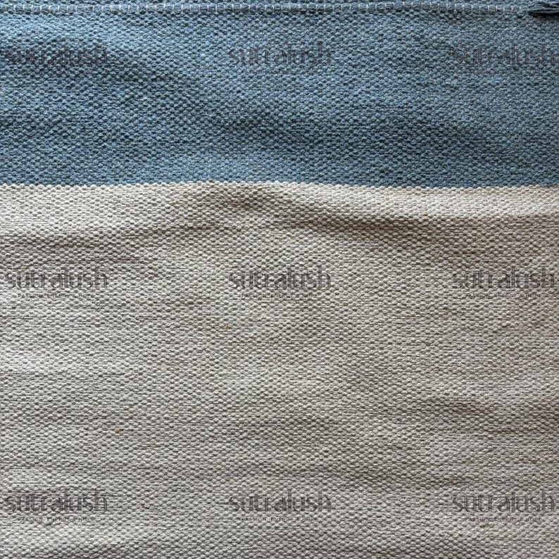 Peut inclure: Textile tiss&eacute; &agrave; surface textur&eacute;e. Le motif pr&eacute;sente des bandes horizontales bleu clair et blanc cass&eacute;. Le mot "sutralush" est imprim&eacute; &agrave; plusieurs reprises sur le textile.