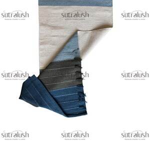 Peut inclure: Tapis rectangulaire multicolore avec un coin pli&eacute;. Le tapis pr&eacute;sente des rayures horizontales dans les tons de bleu, de gris et de beige. Le coin pli&eacute; r&eacute;v&egrave;le un dessous beige clair. Le tapis a une bordure frang&eacute;e.