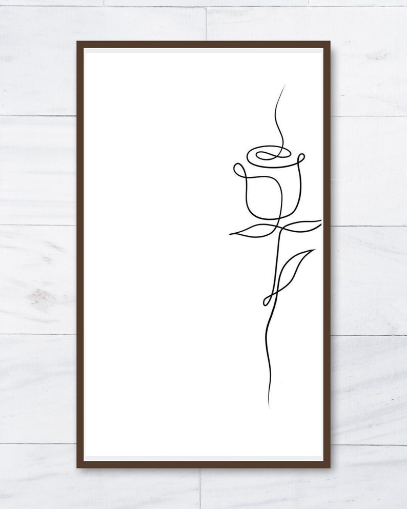 K&ouml;nnte beinhalten: Ein gerahmter Druck mit einer minimalistischen Strichzeichnung einer Rose. Der schwarze Umriss der Blume ist vor einem wei&szlig;en Hintergrund mit einem braunen Rahmen abgebildet. Das Kunstwerk zeigt eine einzelne Rose mit Stiel und Bl&auml;ttern.
