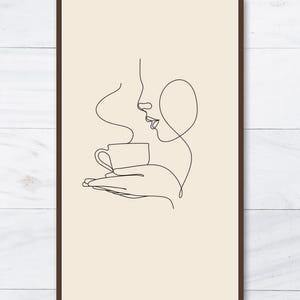 K&ouml;nnte beinhalten: Gerahmter Kunstdruck mit einer minimalistischen Strichzeichnung eines Personenprofils, das eine Kaffeetasse h&auml;lt. Die schwarze Linienkunst befindet sich vor einem beigefarbenen Hintergrund, in einem dunkelbraunen Rahmen. Der Dampf aus der Kaffeetasse ist ebenfalls dargestellt.