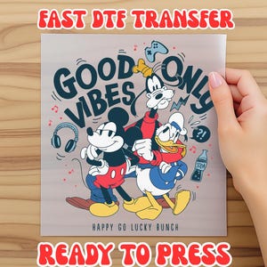 May include: A DTF transfer featuring Mickey Mouse, Goofy, and Donald Duck with the text "GOOD VIBES ONLY" and "HAPPY GO LUCKY BUNCH". The transfer includes a soda bottle, headphones, and a game controller. The text "FAST DTF TRANSFER" and "READY TO PRESS" are also visible.